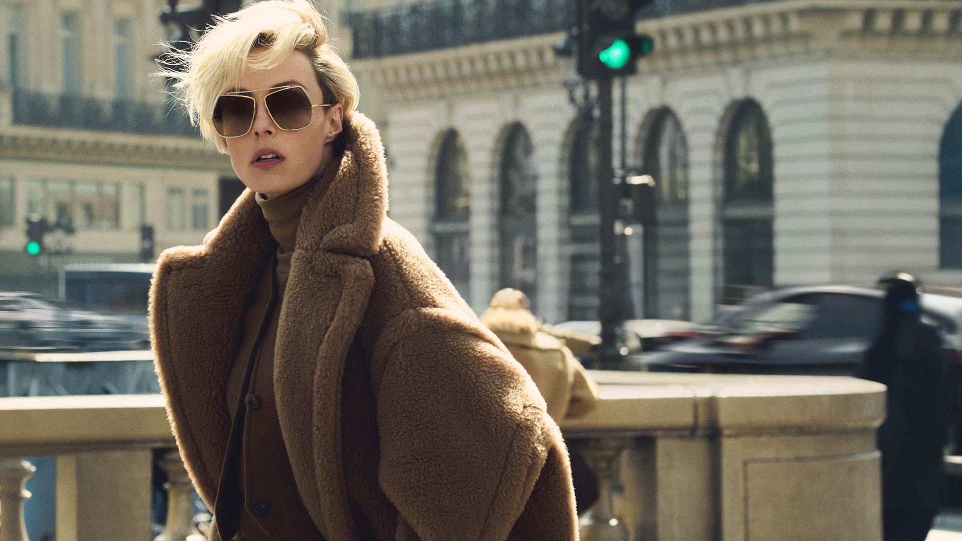 Model with Max Mara long Teddy Bear icon coat in camel colour, in a dynamic urban environment.